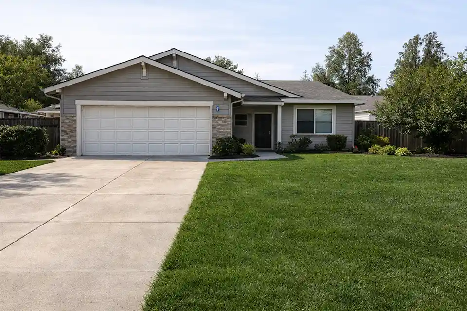 Suburban front yard with garage-heavy facade, too much lawn, and weak entry focus