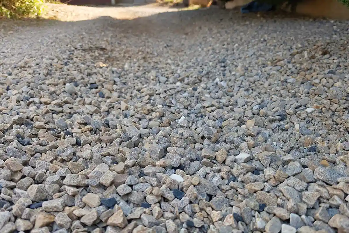 Close-up of a small lawn-free gravel yard where the surface appears dry but may feel unstable or slick underfoot.