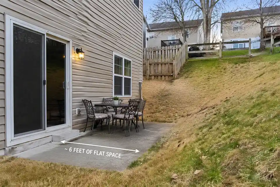 Small flat patio area in a sloped backyard with overlay showing limited usable level space before the slope begins.