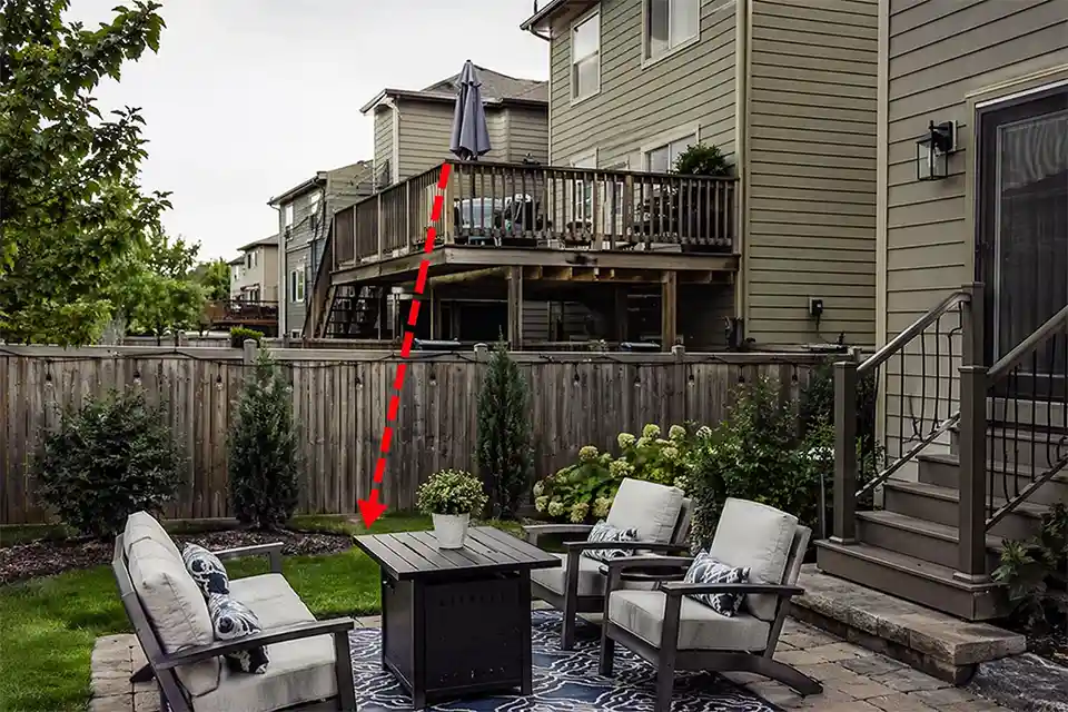 Backyard patio with a neighbor’s elevated deck overlooking the seating area and a simple overlay showing the direct downward sightline