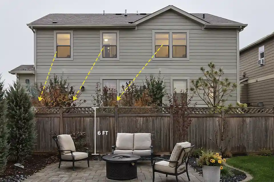 Backyard patio exposed to second-story neighbor windows with overlay showing downward sightlines over a standard privacy fence