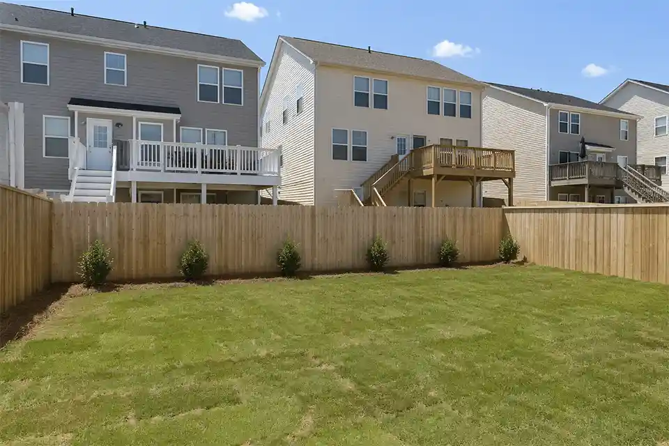 New construction backyard with small shrubs, standard fence, and direct visibility from nearby second-story homes