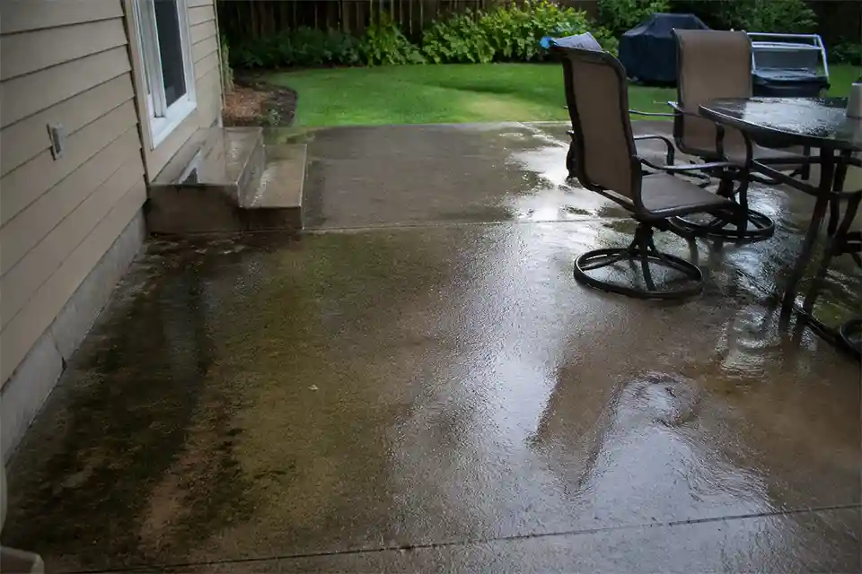 Slippery concrete patio with wet sheen and dark algae buildup along a shaded edge